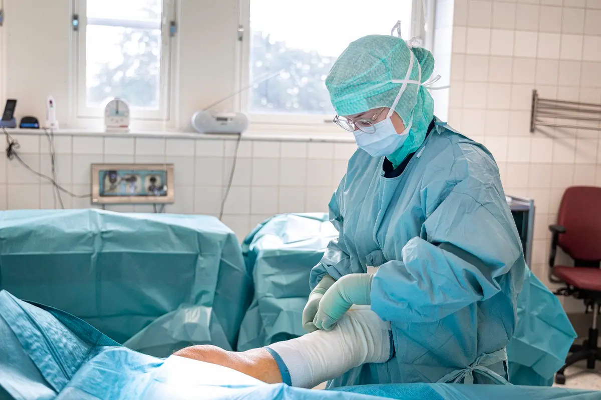 Operationssjuksköterska lindar om benet på en patient