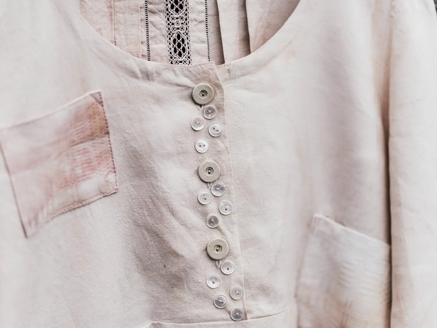 Närbild på en blus eller skjorta med många knappar sydda som dekoration på knappslån.