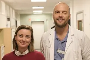 En kvinna och en man står bredvid varandra i en sjukhuskorridor.