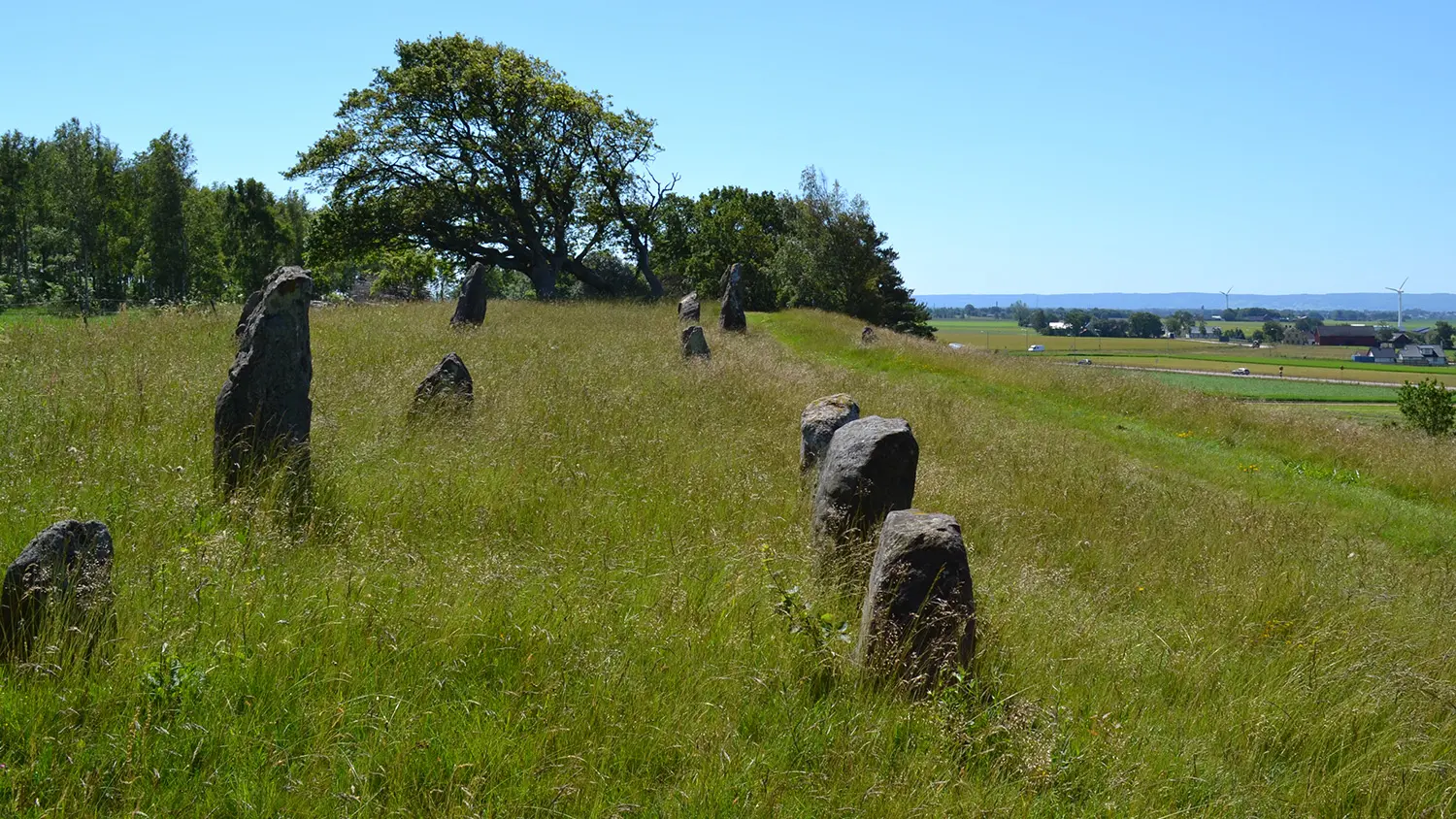 Resta stenar från äldre järnålder och utsikt mot havet vid horisonten.