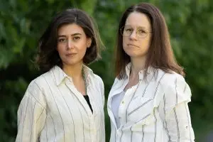 Två kvinnor med mörkt hår och randiga vita skjortor.