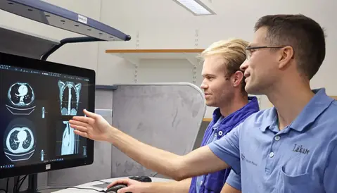Två läkare tittar på röntgenbilder på en datorskärm.